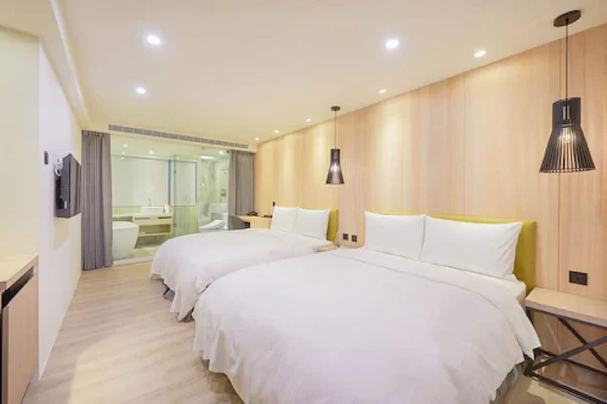 Une chambre d’hôtel avec deux lits, une salle de bain et une douche en verre.
