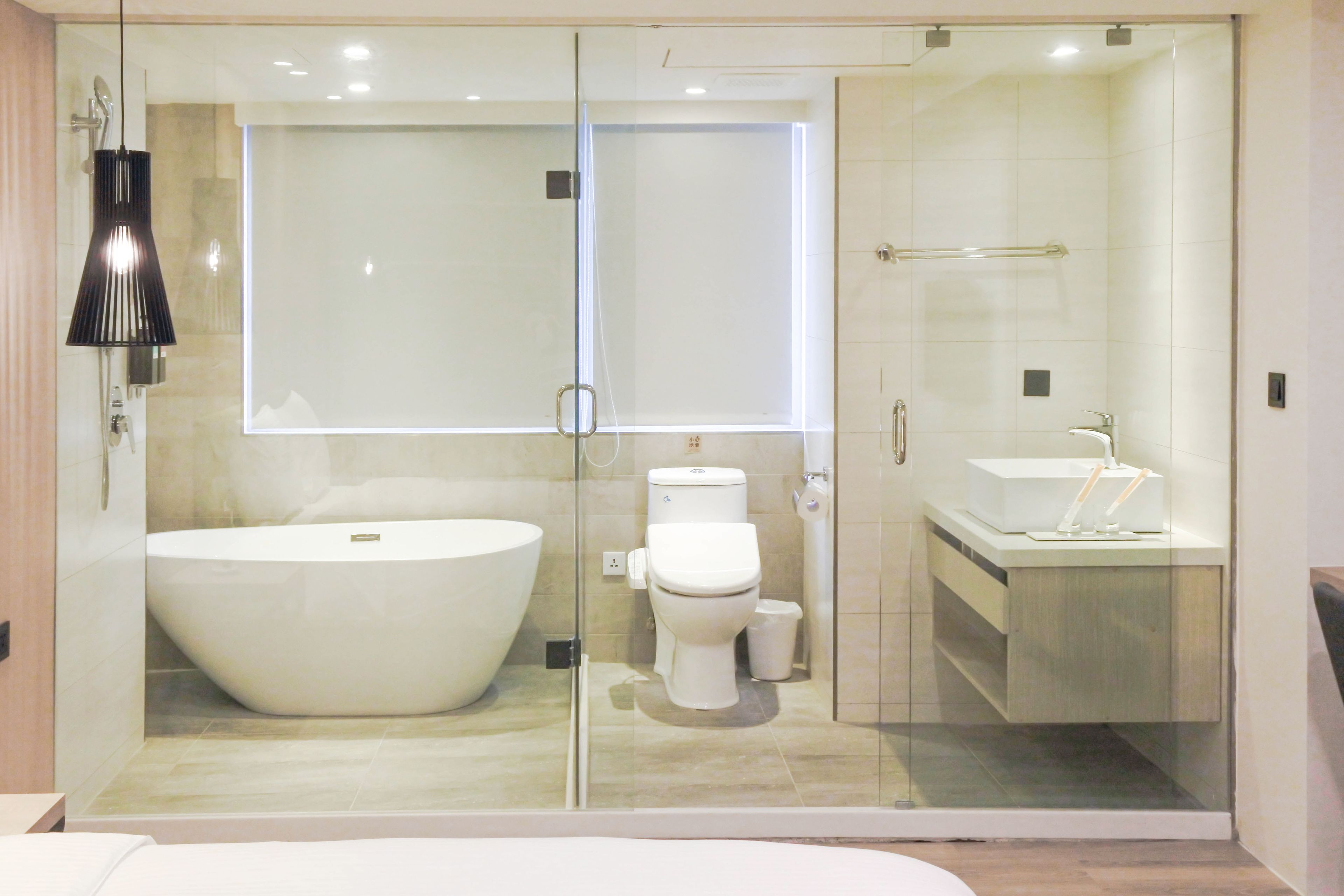 A modern bathroom with a large freestanding bathtub, a glass-enclosed shower area, and a separate sink.