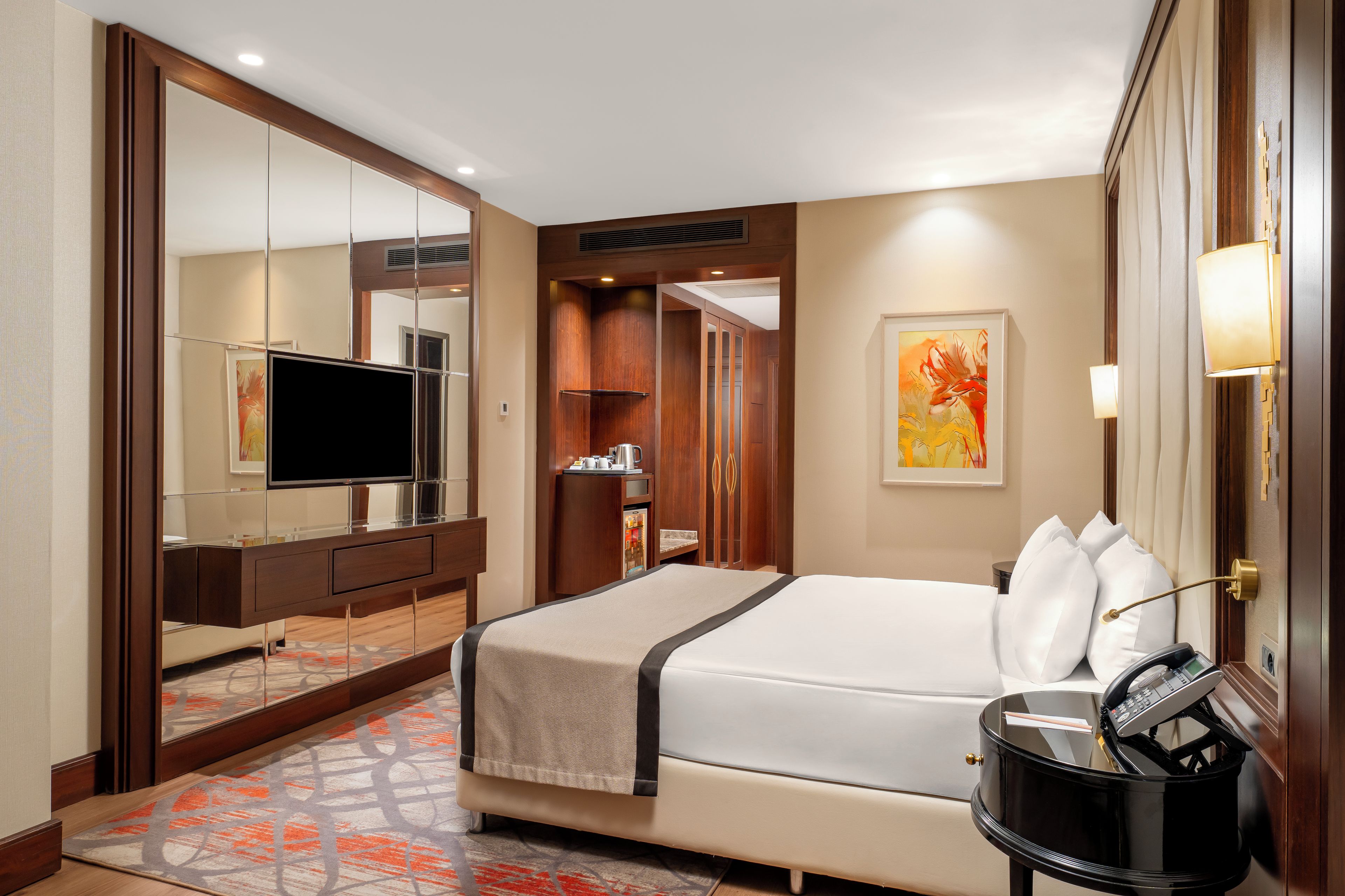 Habitación de hotel con cama, televisión, minibar y baño con ducha e inodoro.