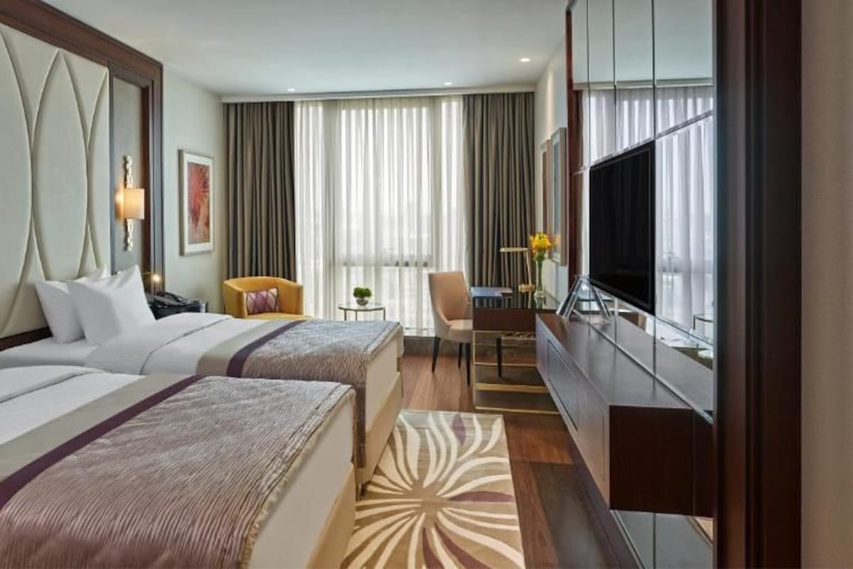 Une chambre d’hôtel avec deux lits, une télévision, un bureau et une chaise.