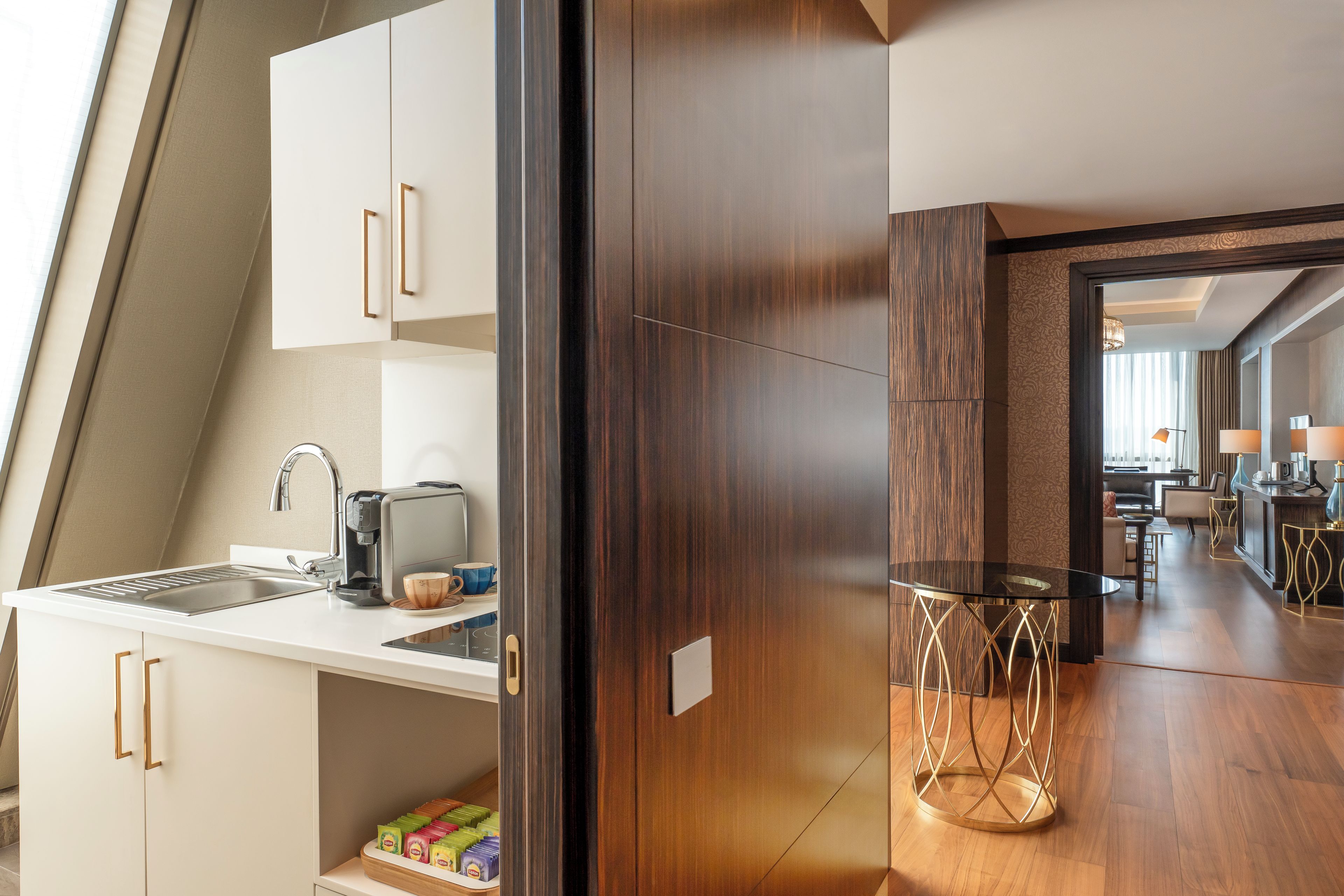 A modern kitchen with a built-in coffee maker, a sink, and a cup on the counter.
