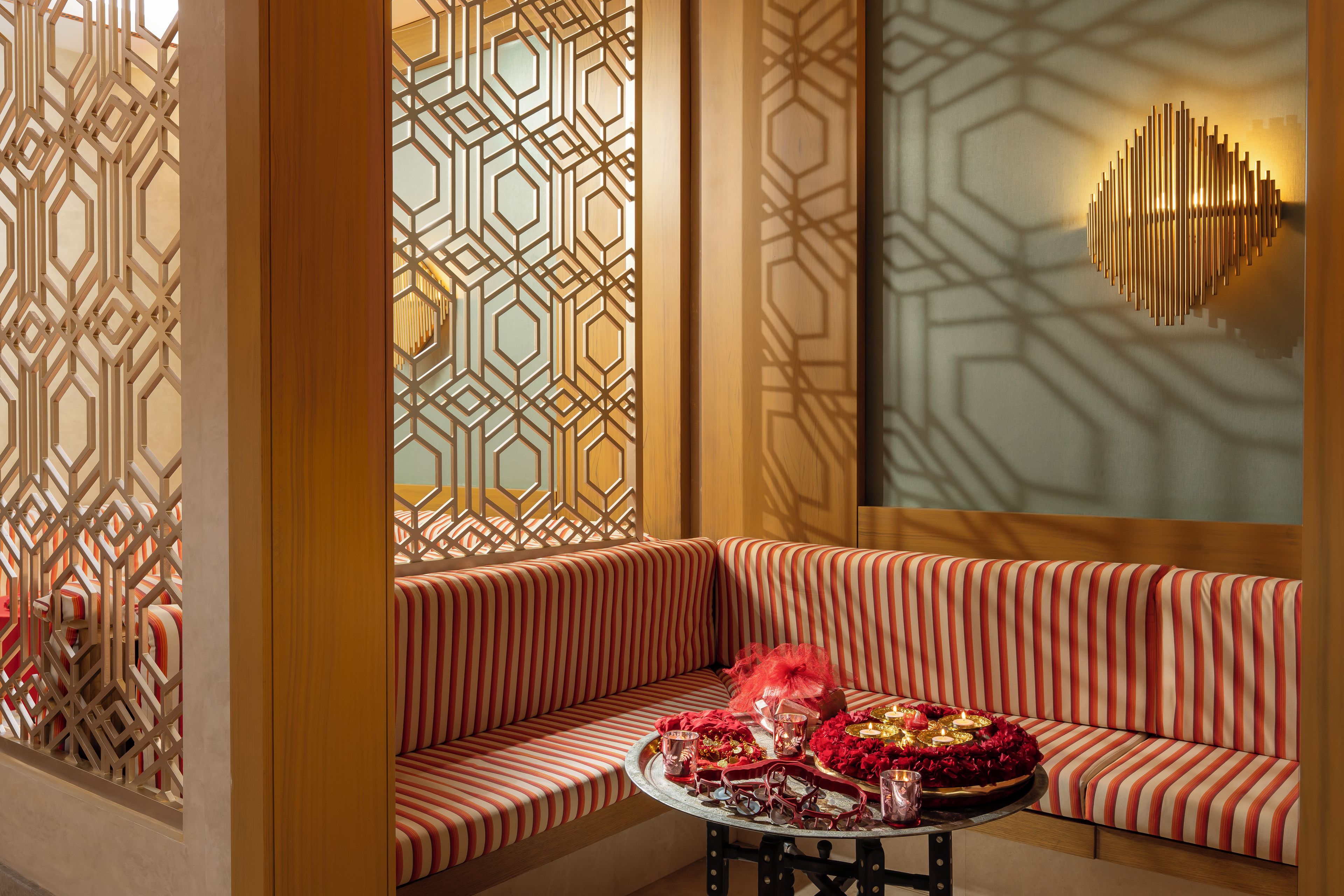 A room with a patterned partition, a cushioned seating area, and a table with decorative items.