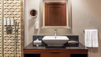 A bathroom with a sink, mirror, and toiletries.