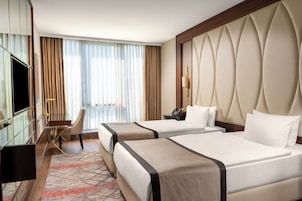 Habitación de hotel con dos camas, un escritorio, una silla y un televisor.
