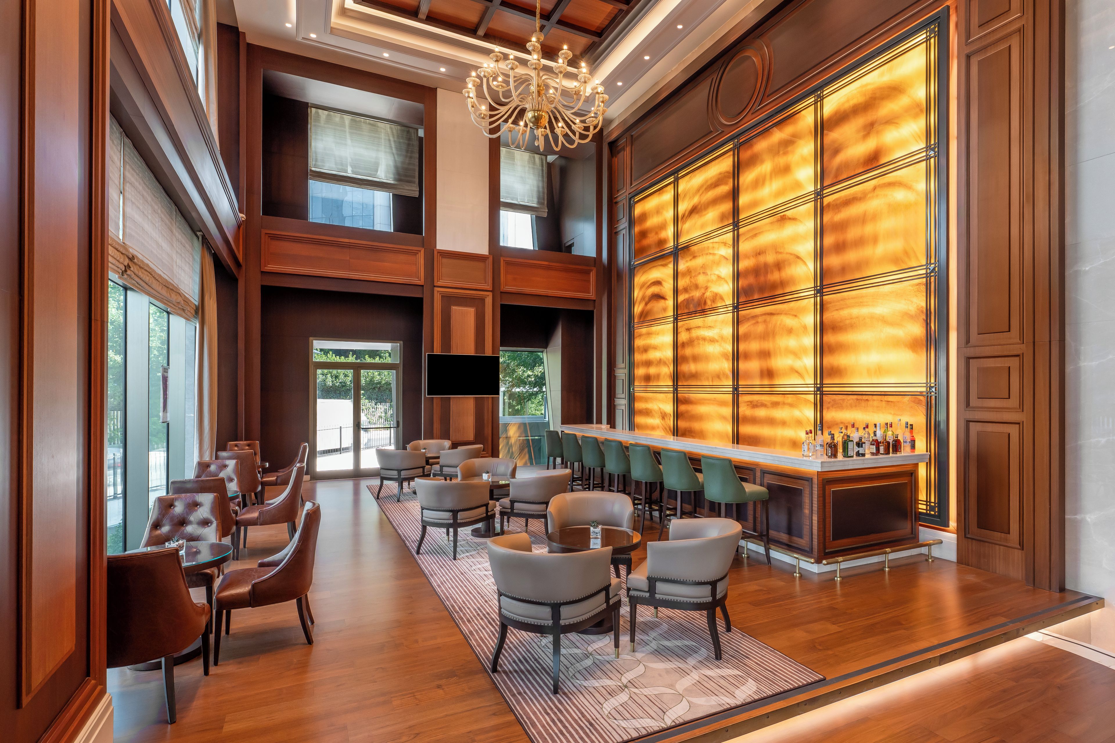 A spacious lobby with a bar area, seating arrangements, and a large window providing a view outside.
