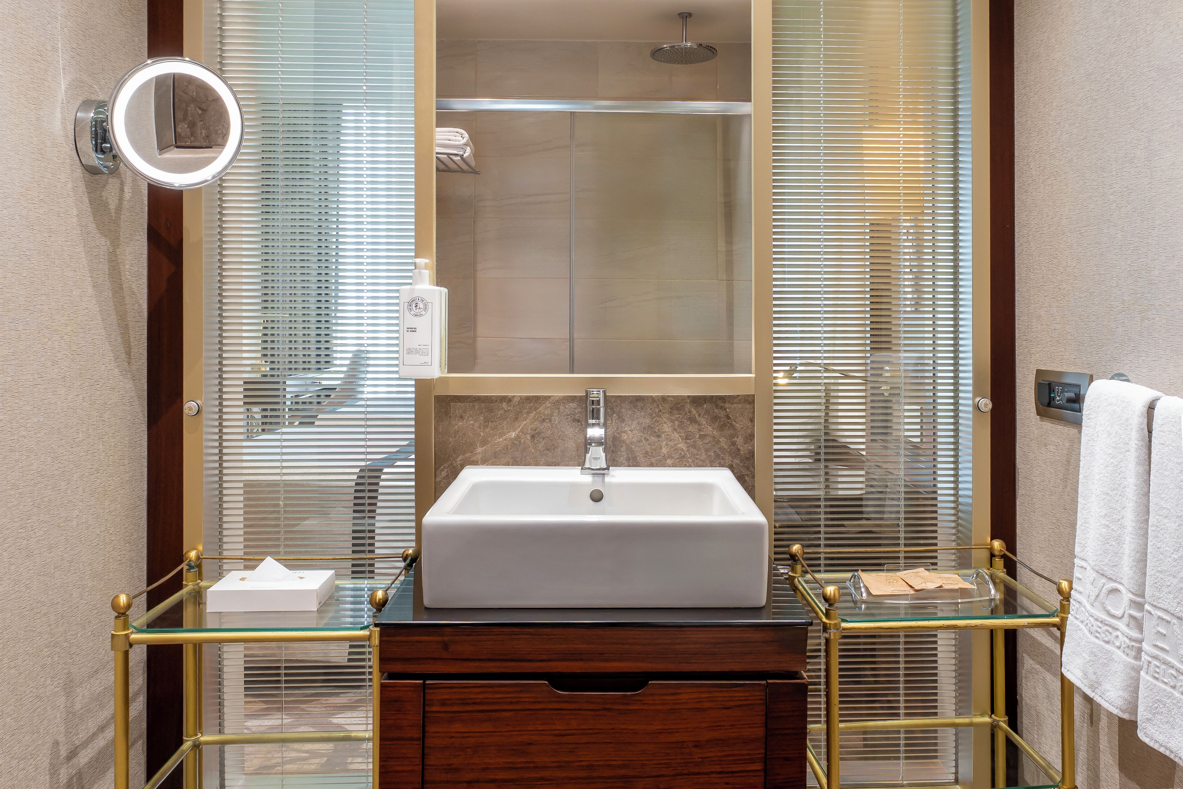 Une salle de bain avec un lavabo blanc, un miroir, une cabine de douche en verre et un porte-serviettes.