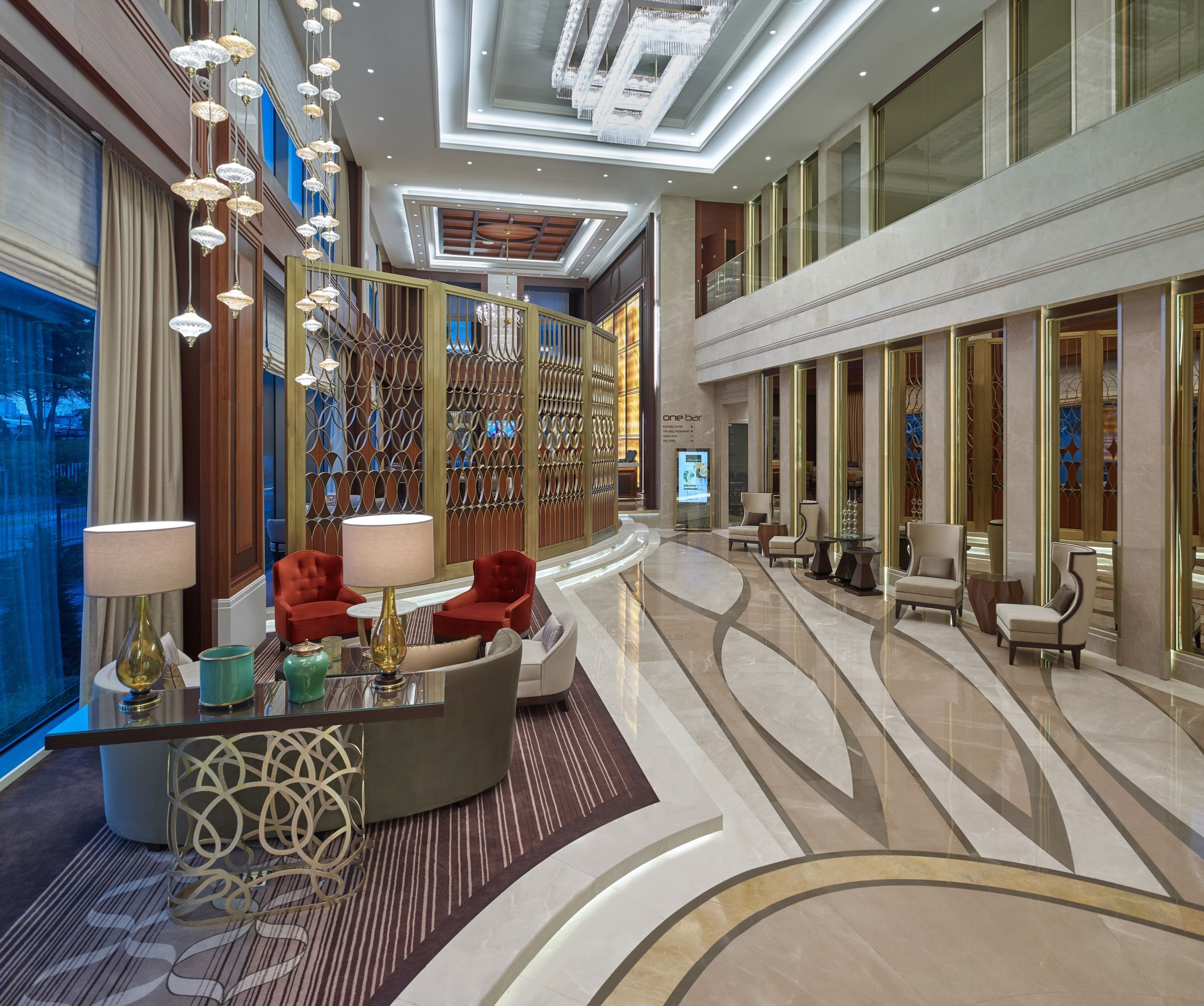 A modern lobby with a curved reception desk, seating area, and a decorative wall with geometric patterns.