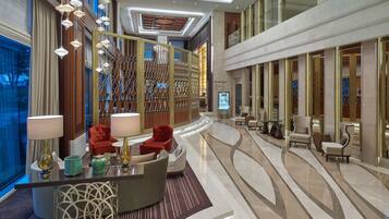 A modern lobby with a curved reception desk, seating area, and a decorative wall with geometric patterns.