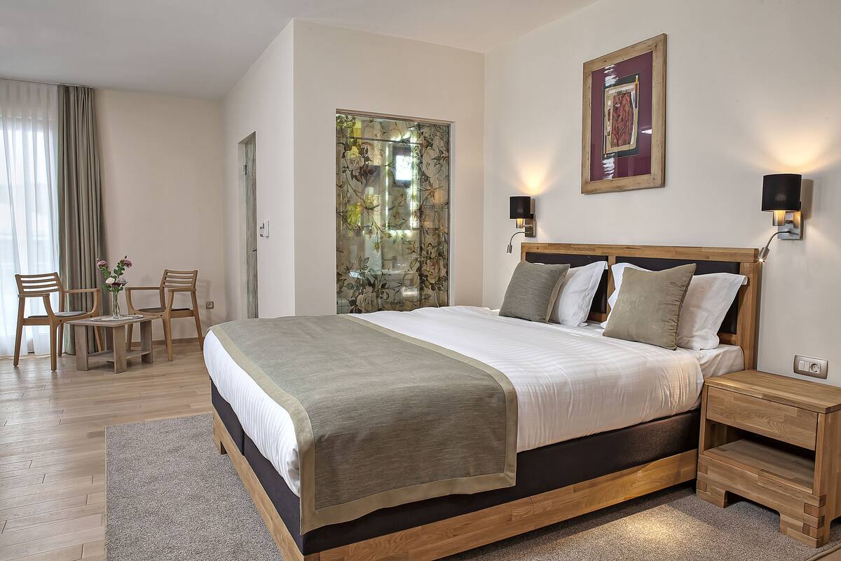 A neatly arranged bedroom with a large bed, bedside tables, a desk, and chairs.