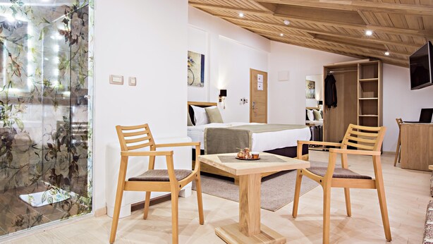 Une pièce comprenant un lit, deux chaises en bois, une petite table et un plafond en bois.