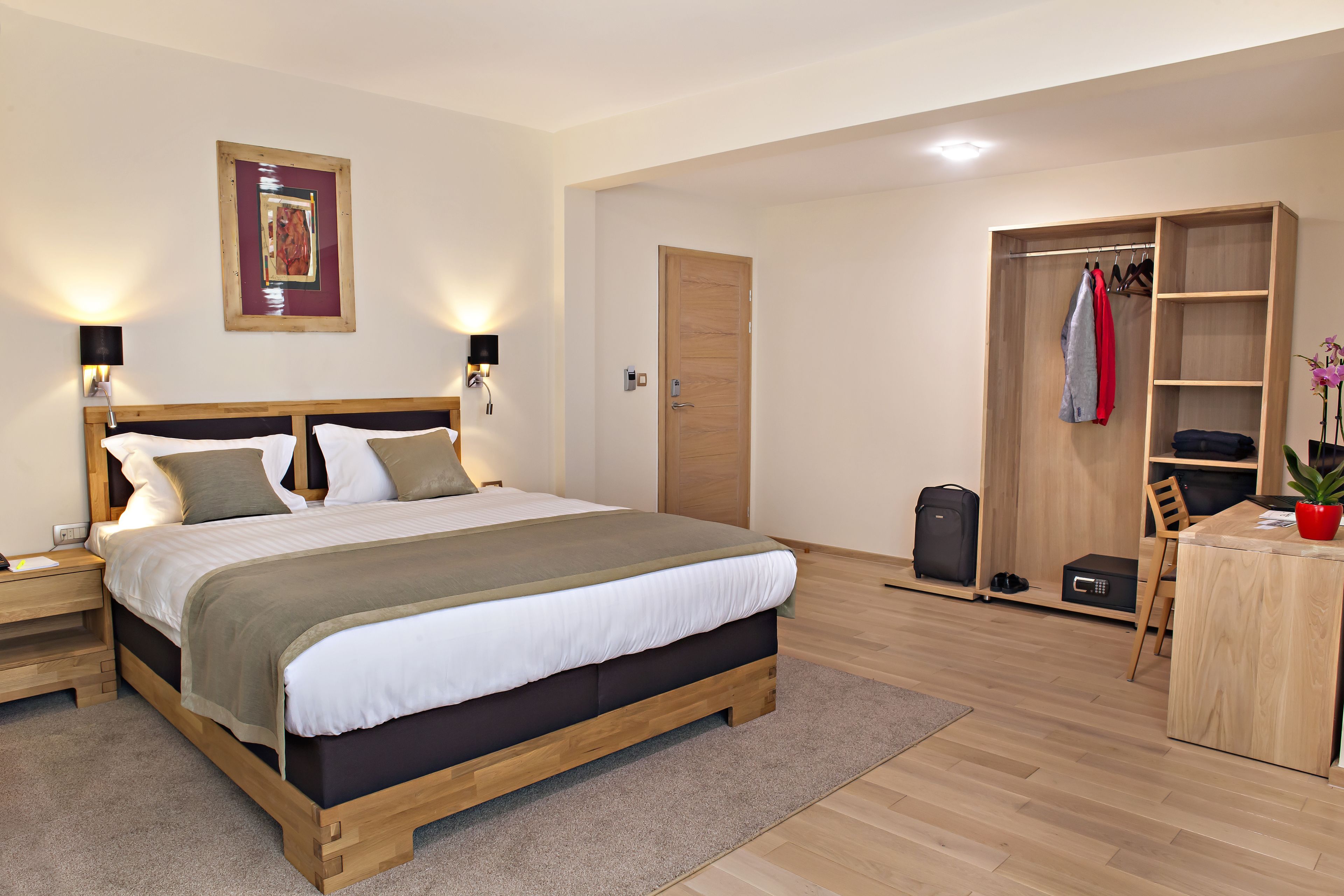A modern bedroom with a wooden bed, bedside tables, a wardrobe, and a desk area.