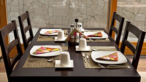 Une table à manger dressée avec des assiettes, des couverts et des serviettes, entourée de chaises.