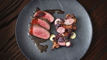 A plate with sliced meat, vegetables, and a sauce.
