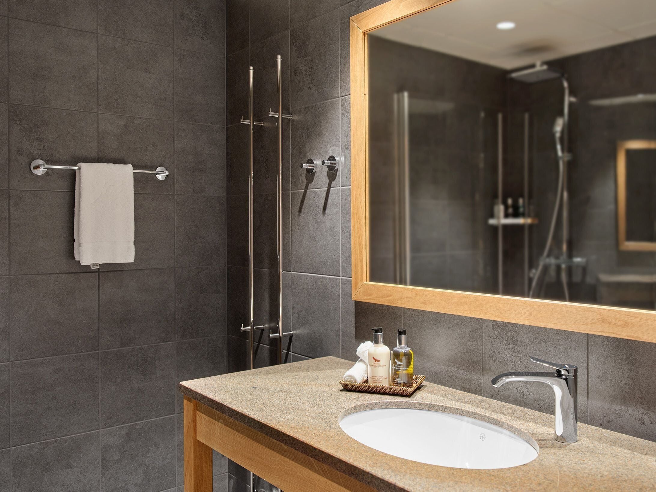 A modern bathroom with a large mirror, a sink, and a shower area.