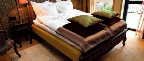 A bed with pillows, a bedside table, a chair, and a window with a view.