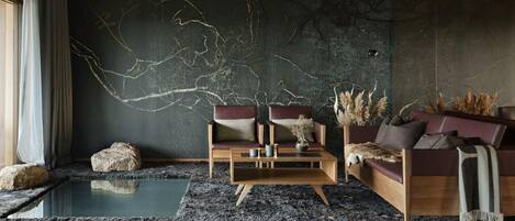 A modern living room with a stone wall, a wooden coffee table, two sofas, and a large horn sculpture.
