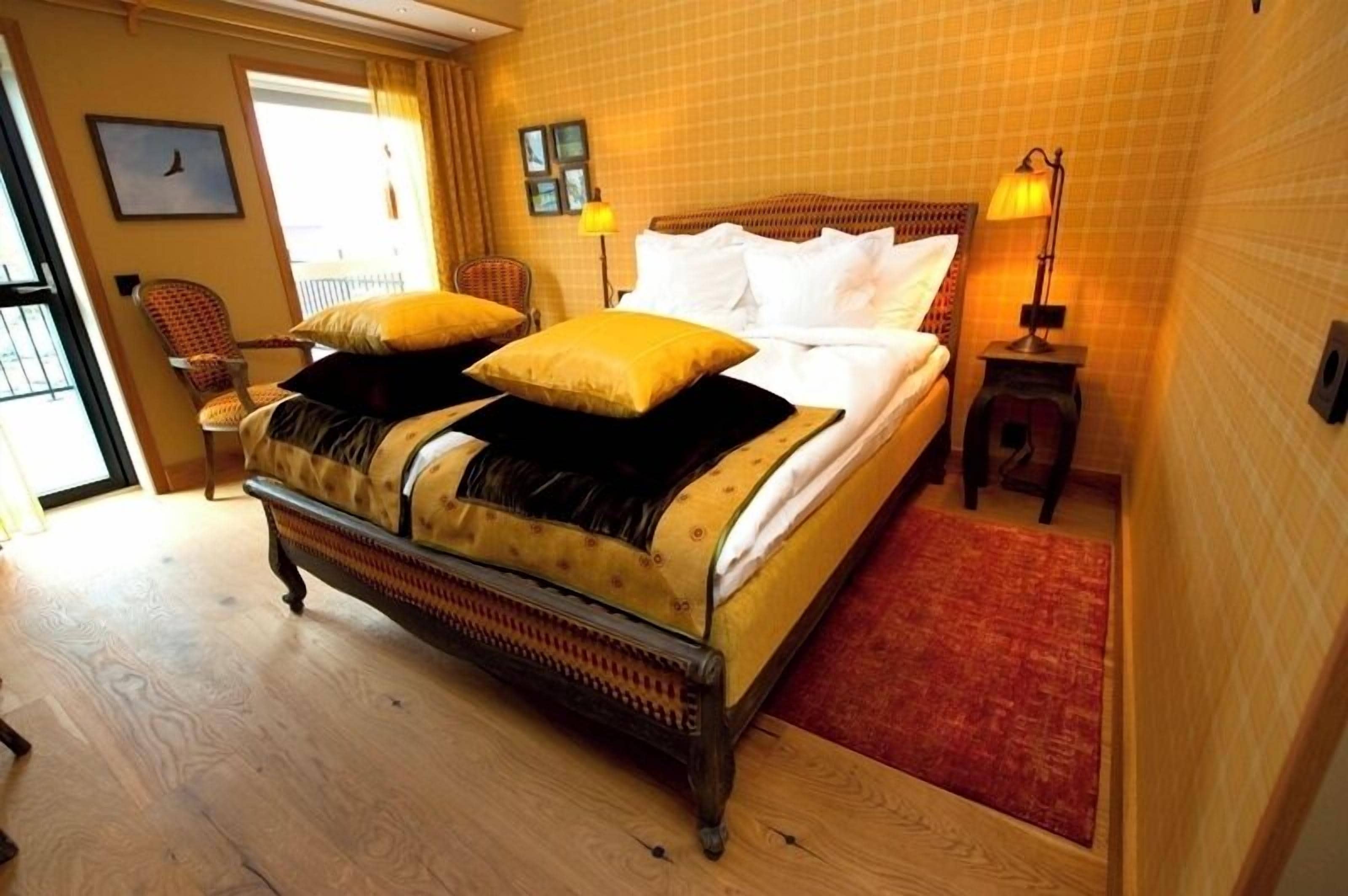 A bedroom with a large bed, a chair, a nightstand, and a window.