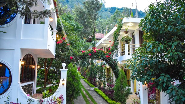 Un edificio blanco con un camino de jardín que conduce a un balcón.