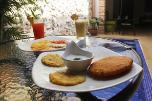 A meal with fried items, a bowl of sauce, and a drink on a glass table.