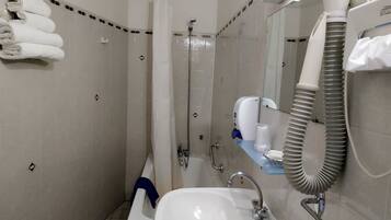 A bathroom with a sink, mirror, towel rack, shower, and a hand dryer.