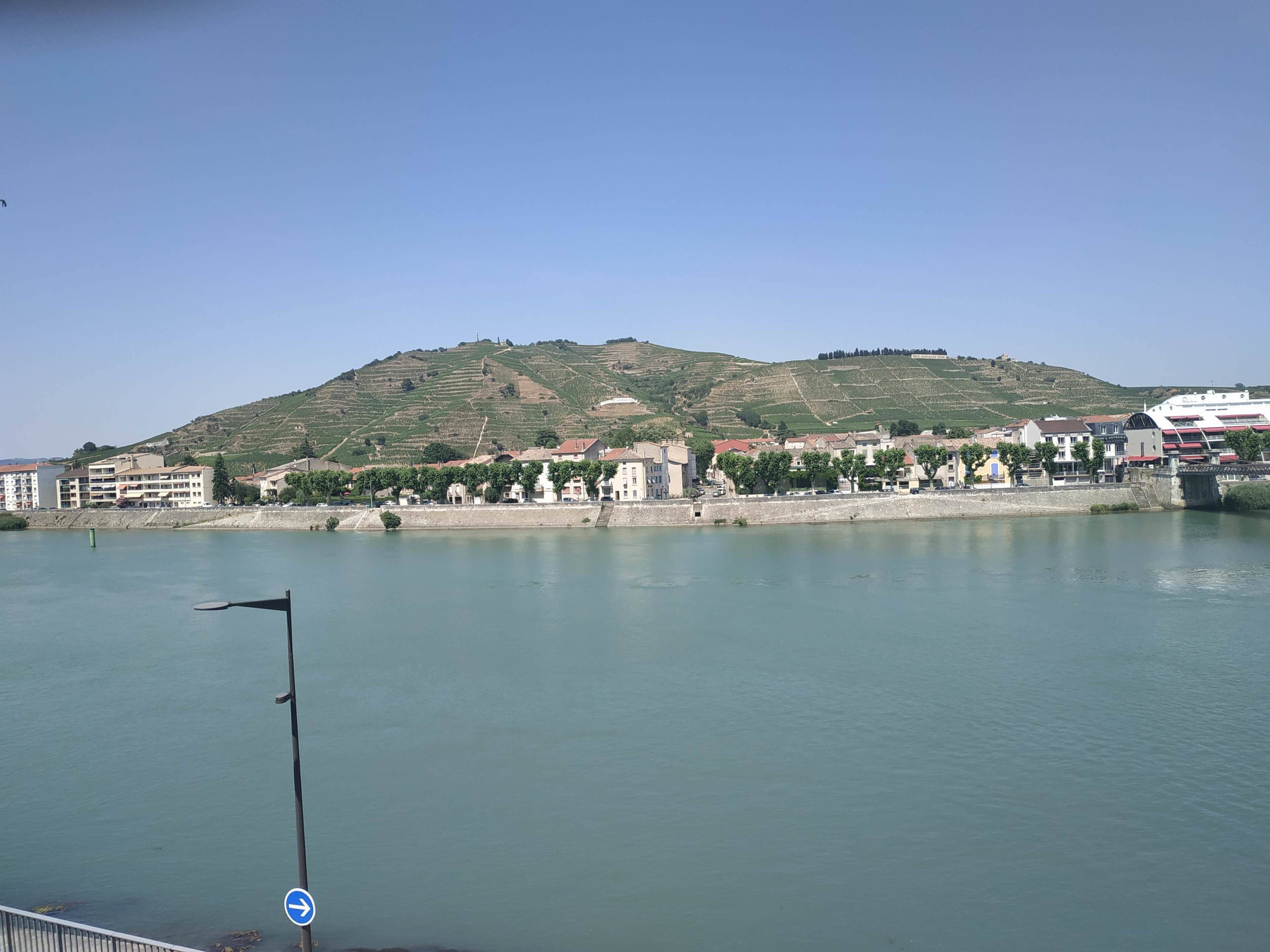 Vista al río con edificios, una colina y un puente.