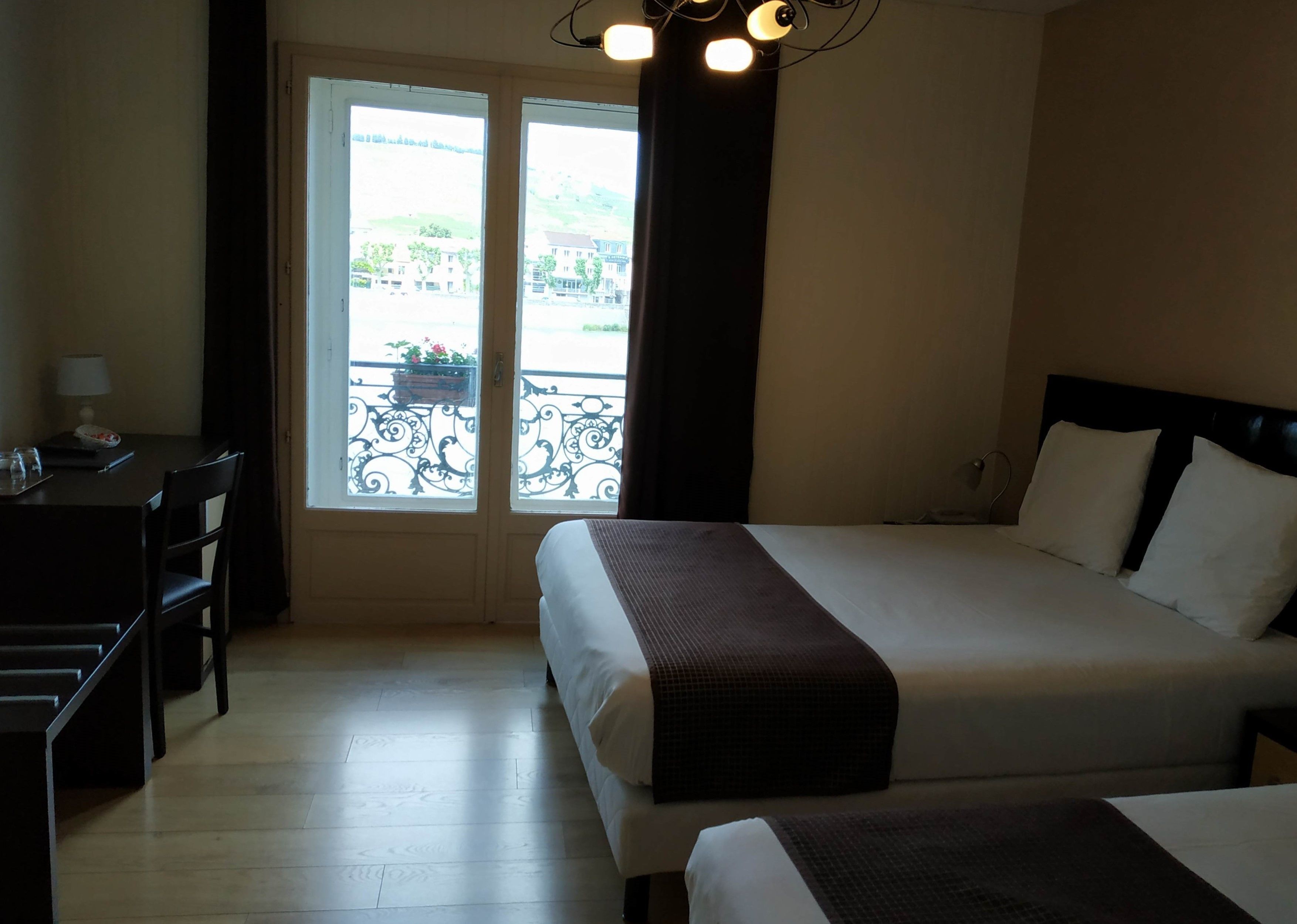 Ein Hotelzimmer mit einem Bett, einem Schreibtisch und Blick durch eine Tür nach draußen.