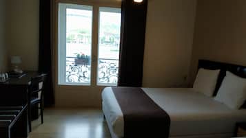 Ein Hotelzimmer mit einem Bett, einem Schreibtisch und Blick durch eine Tür nach draußen.