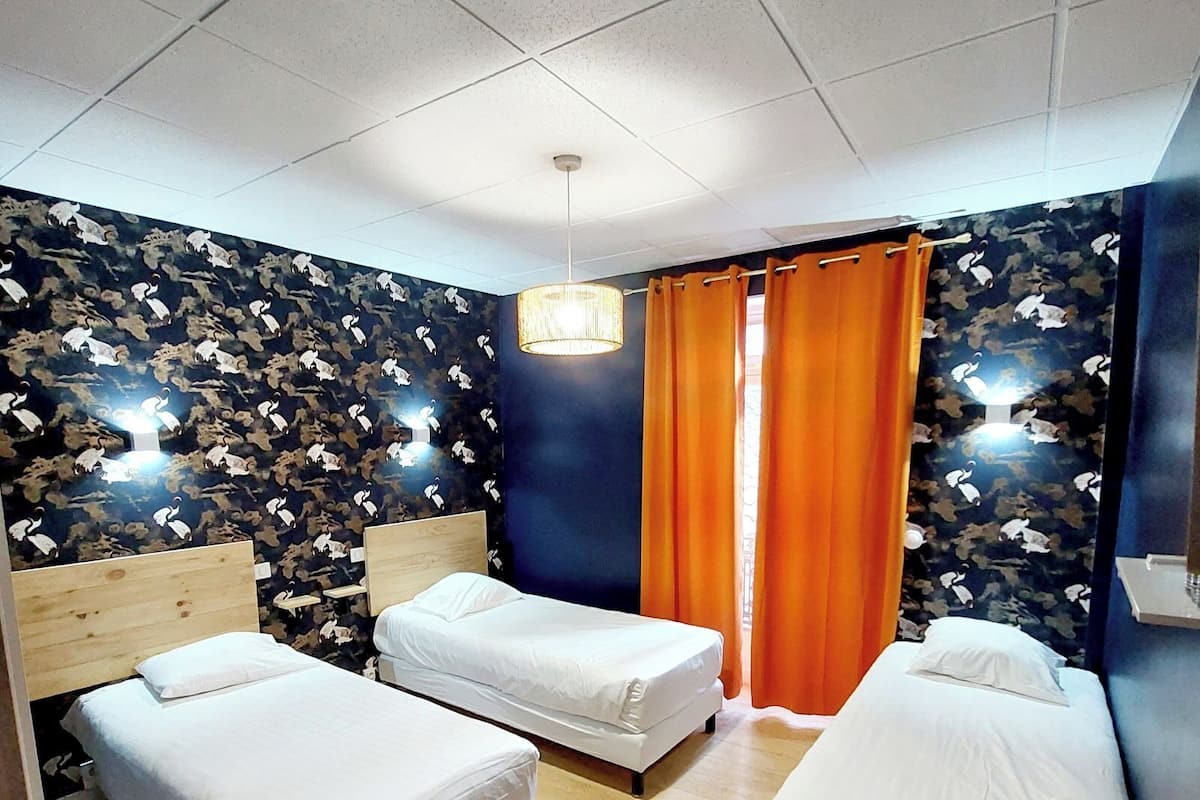 A hotel room with two single beds, a wooden desk, and a patterned wall.