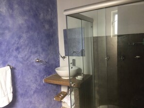 Um banheiro com box de vidro, pia branca e porta-toalhas.
