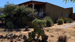 A two-story building with a flat roof, a balcony with a metal railing, and a cactus in the foreground. - Casa Tulipan (San Miguel de Allende)