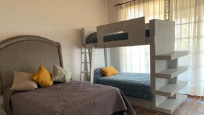 A bedroom with a large bed, two bunk beds, and a ladder. - Casa Tulipan (San Miguel de Allende)