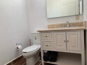 A bathroom with a toilet, a sink, a mirror, and a towel rack. - Casa Tulipan (San Miguel de Allende)