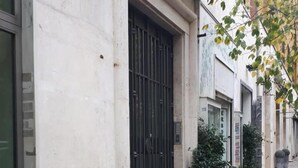 A row of buildings with a white facade, a black metal gate, and a small potted plant on the sidewalk. - Cinque Sogni (Rome)