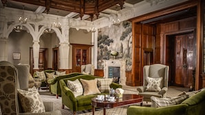 Una sala de estar formal con sofás verdes, sillones estampados y una chimenea.