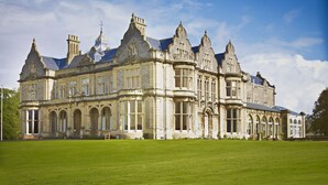 A large, historic building with multiple towers and arched windows, surrounded by a well-maintained lawn. - Clevedon Hall (Clevedon)