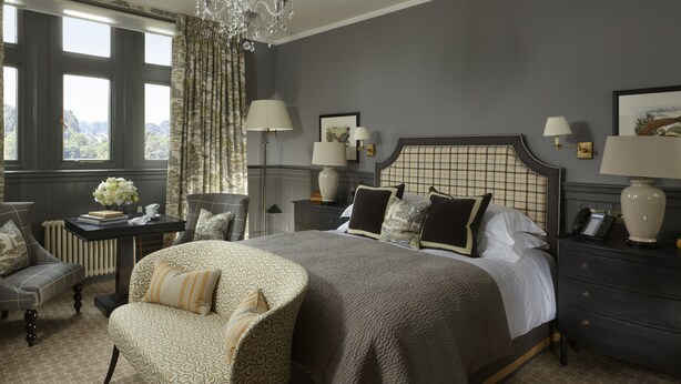 A bedroom with a large bed, two bedside tables with lamps, a chair, and a chandelier. - Clevedon Hall (Clevedon)