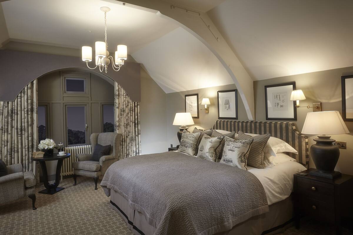 Un dormitorio con una cama grande, una silla, una mesa y una araña.