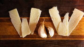Varios trozos de queso blanco y un bulbo de ajo sobre una superficie de madera.