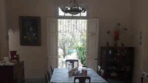 Un comedor con una mesa redonda, sillas, una araña y vistas por una ventana.