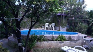 Una piscina con dos sillas de plástico blanco y una pequeña mesa.