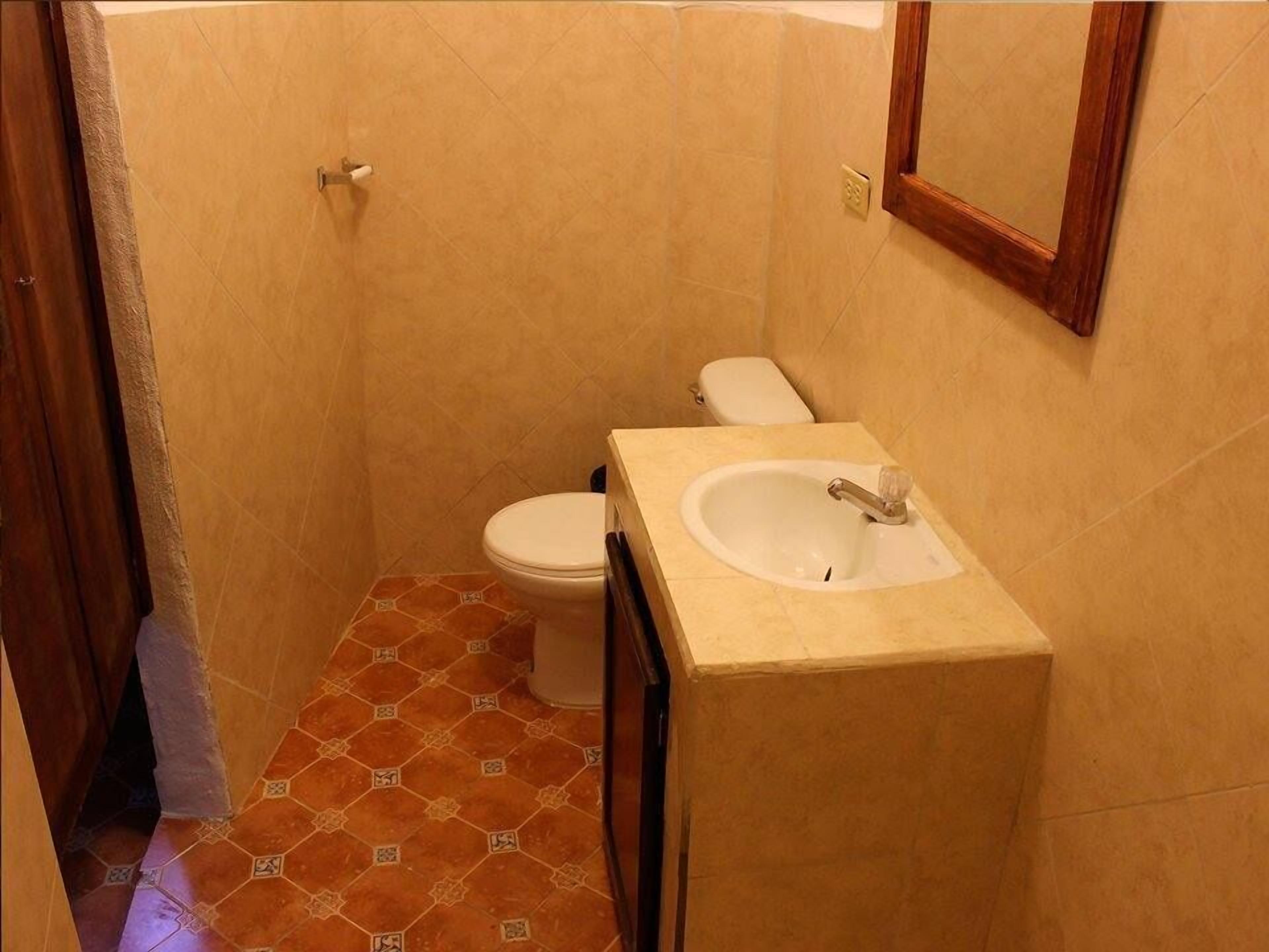 Ein kleines Badezimmer mit Toilette, Waschbecken und Fliesenboden.
