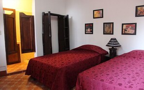 Une chambre avec deux lits, une armoire en bois, une porte et un mur orné de tableaux.