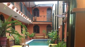 Ein Essbereich mit einem für zwei gedecktem Tisch, einem Pool im Hintergrund und umgebenden Topfpflanzen.