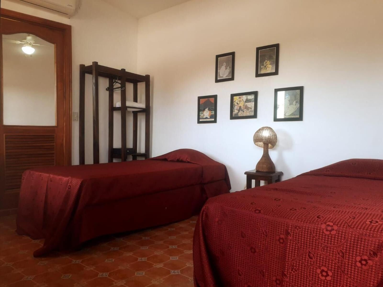 A room with two beds, a wooden wardrobe, and several framed pictures on the wall.