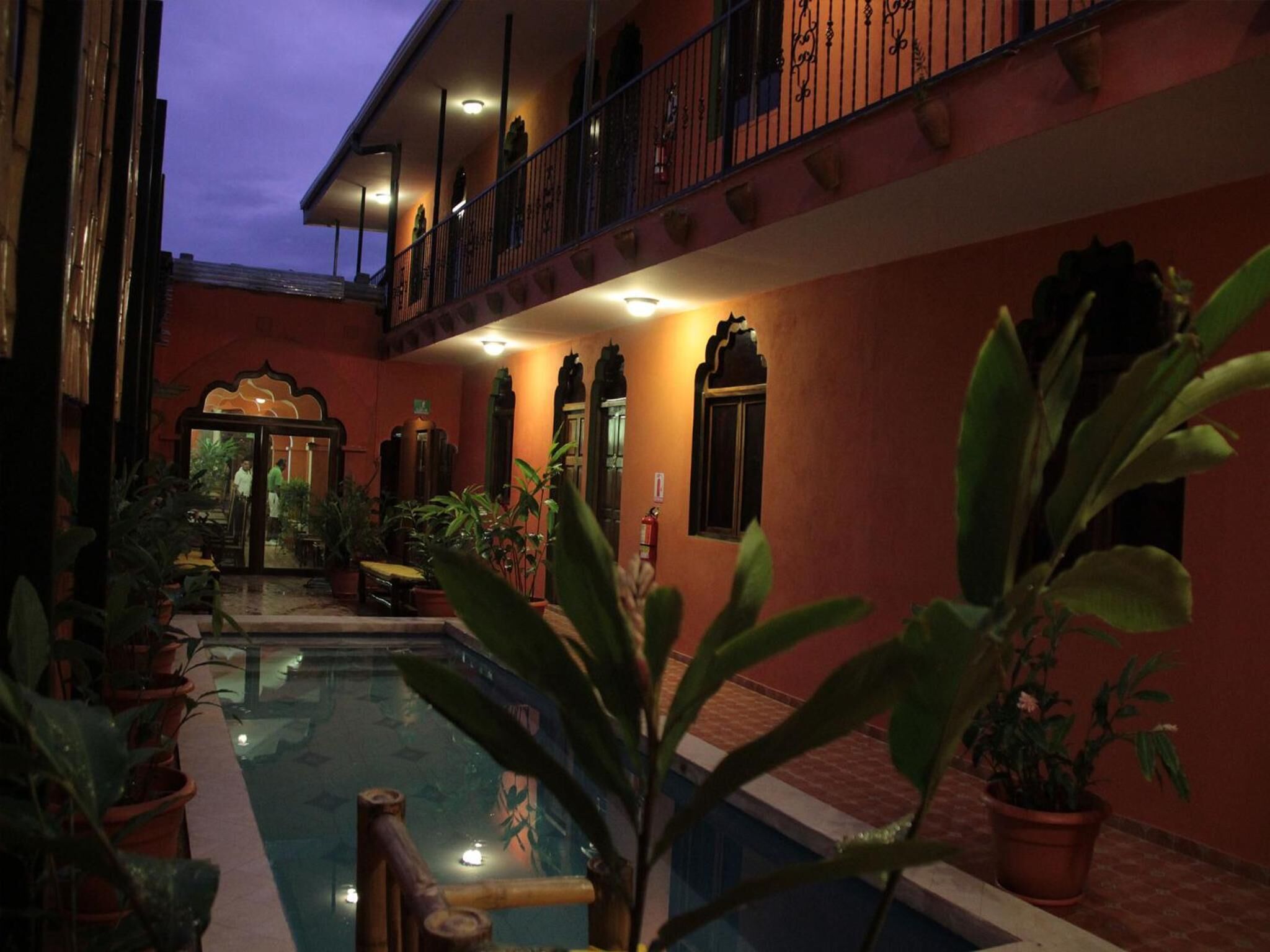 Un cortile con piscina, piante in vaso e un edificio con un balcone.