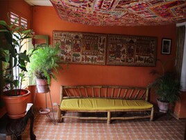A room with a wooden bench, terracotta floor, and a colorful ceiling.