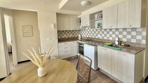 Una cocina moderna con armarios de madera clara, encimera de granito y comedor con una mesa redonda y sillas.