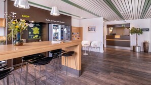 A modern hotel lobby with a reception desk, bar area, and seating. - B&B HOTEL La Rochelle Centre (La Rochelle)