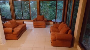 Quarto com grandes janelas, um conjunto de sofás e uma pequena mesa.