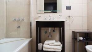 Ein modernes Badezimmer mit Duschkabine aus Glas, einem weißen Waschbecken mit Spiegel darüber und einem Handtuchhalter mit gefalteten Handtüchern.